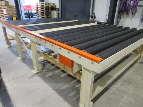 Industrielle Förderanlage mit schwarzen Rollen und oranger Metallkante in Lagerhalle